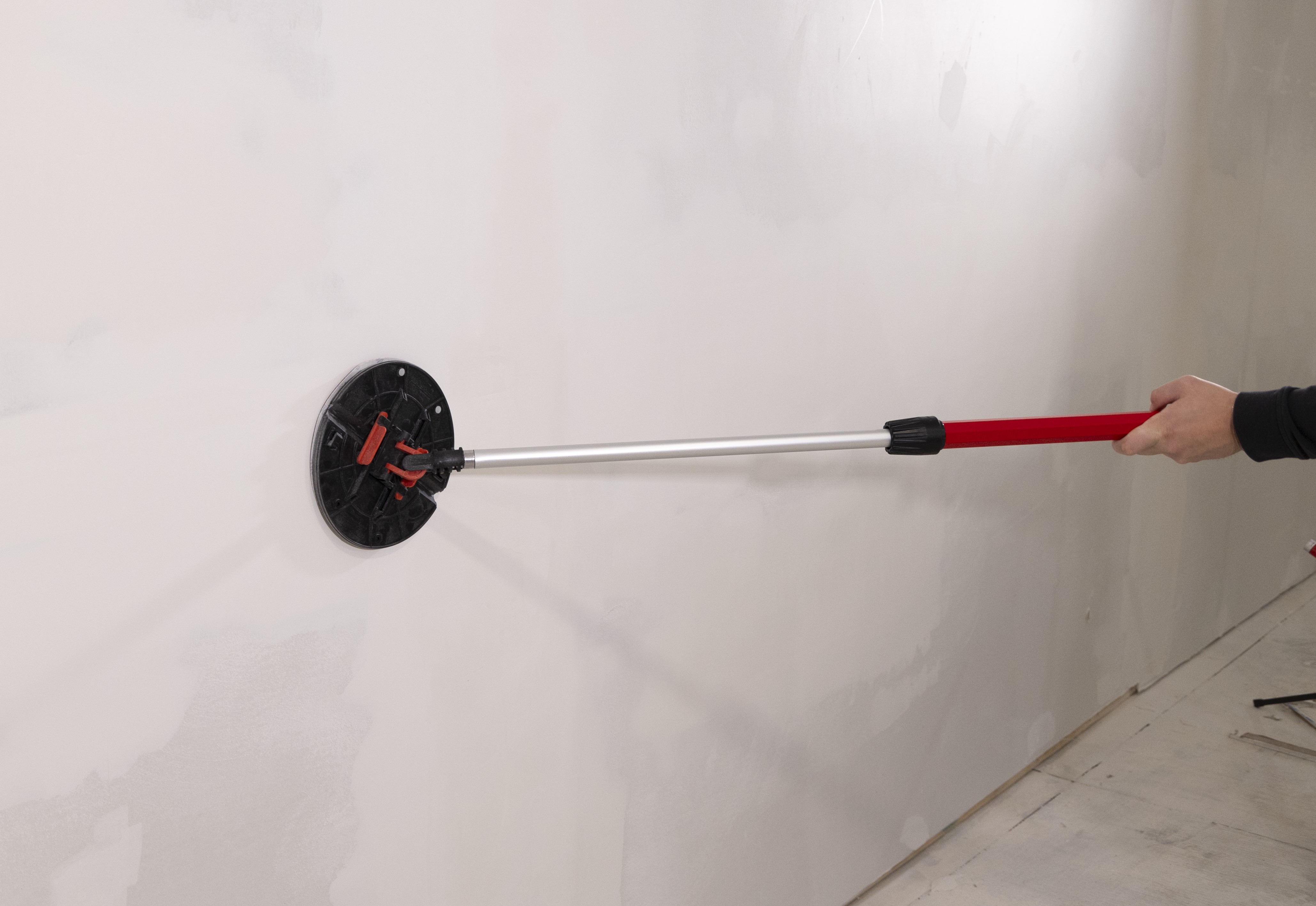 man sanding the wall with the folding radial sander